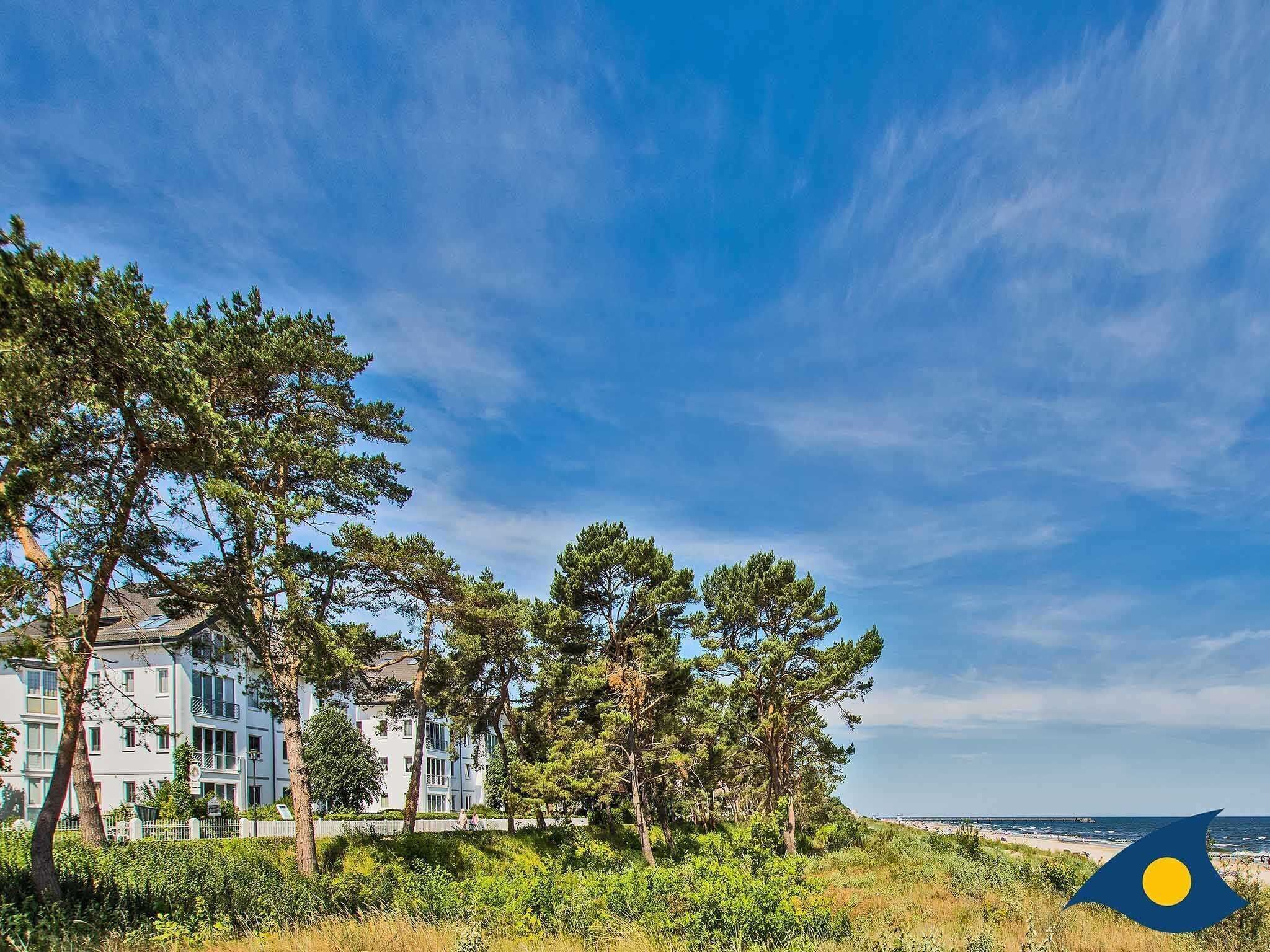 Eine Küstenwohngegend mit mehrstöckigen Gebäuden, üppiger Vegetation und freiem Blick auf den Strand.
