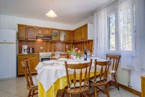A kitchen with wooden cabinets, a dining table with chairs, and a window with curtains.
