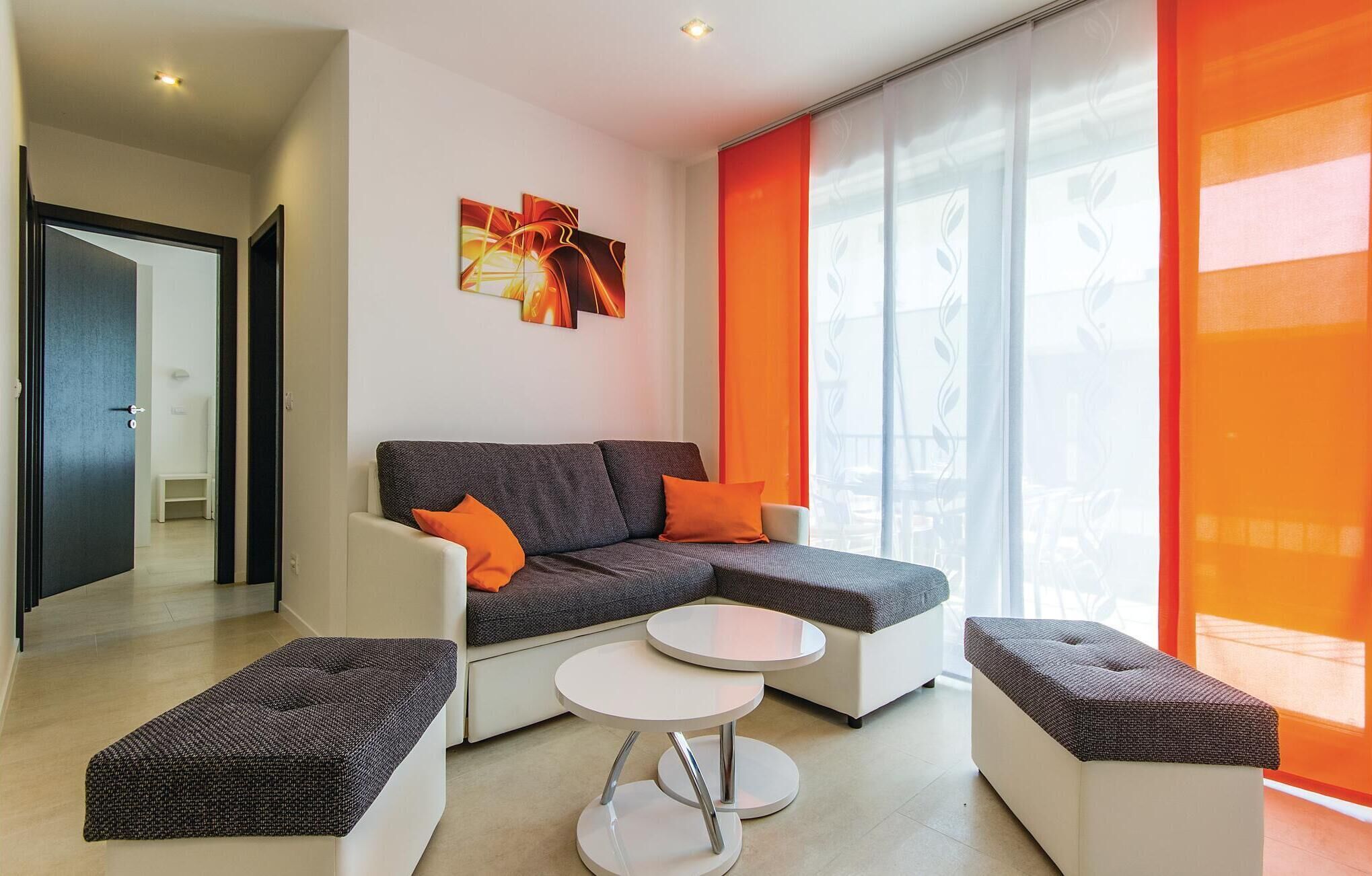 A modern living room with a sectional sofa, two ottomans, and a small round table.
