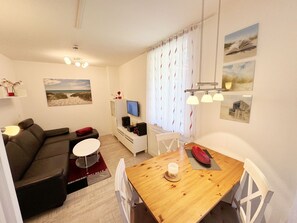 Uma sala de estar moderna com um sofá, uma mesa de jantar e uma televisão.