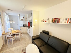 Um espaço de estar compacto com cozinha compacta, área de refeições e estante.