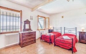 Two single beds with metal frames, a dresser with multiple drawers, and a large window offering a city view.