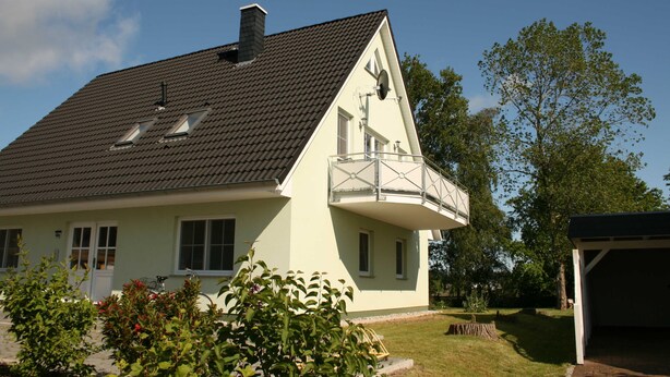 A two-story house with a sloped roof, a balcony, and a garage. - Apartment Wiesenblick 1-1 bedroom up to max. 2 pers. - Vacation home Wiesenblick (Karlshagen)