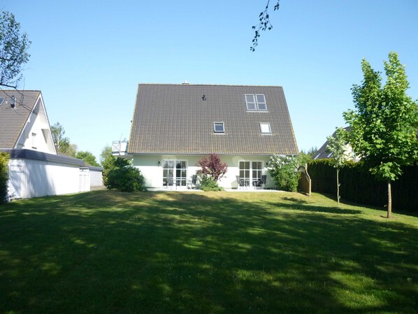 A two-story house with a sloped roof, a front porch, and a well-maintained lawn.