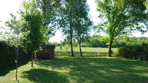 A grassy area with a wooden fence, trees, and a small building. - Apartment Wiesenblick 1-1 bedroom up to max. 2 pers. - Vacation home Wiesenblick (Karlshagen)