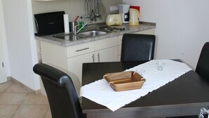 A compact kitchen with white cabinets, a dark wooden dining table, and four chairs. - Apartment Wiesenblick 1-1 bedroom up to max. 2 pers. - Vacation home Wiesenblick (Karlshagen)