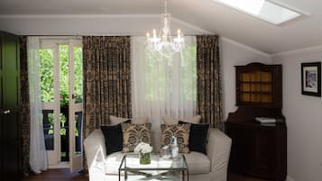 Ein Wohnzimmer mit einer Couch, einem Glastisch, einer Chandelierleuchtre und Blick durch eine Tür.