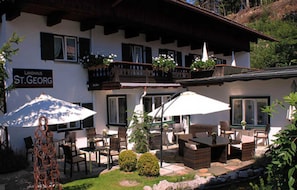 Un edificio con mesas al aire libre, un cartel que dice 'Landhaus St. Georg' y un balcón con macetas.