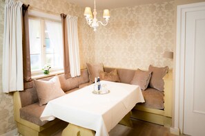 Una habitación con sofá cama, una mesa con una bandeja de objetos, una araña y papel tapiz estampado.