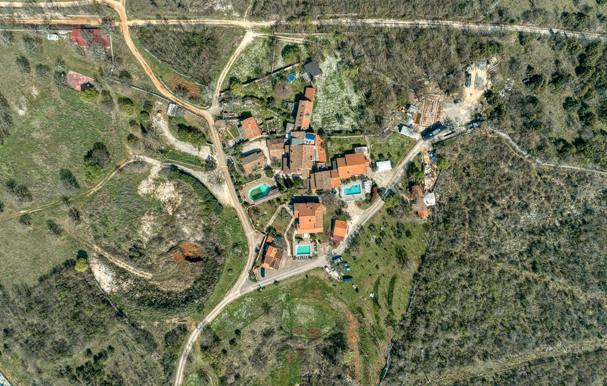 Vista aérea de una zona residencial con varias casas, carreteras y una piscina.