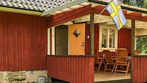 Een houten huis met veranda, een deur en een vlag.