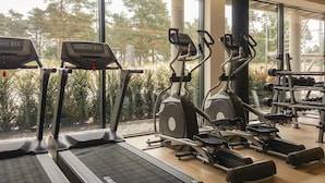 Une salle de sport équipée de tapis de course, de vélos elliptiques et de matériel de musculation.