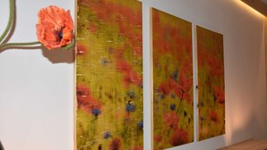 A wall with three abstract paintings and a single flower. - No. 2 Klatschmohnstube - Bauernstube Morgenitz double room (Rankwitz)