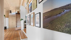 Ein Flur mit Fliesenboden, einer Holztreppe und einem großen Landschaftsbild an der Wand.