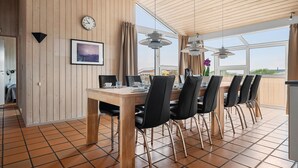 Ein Essbereich mit Holztisch und Stühlen, einer Uhr und einem gerahmten Bild an der Wand.