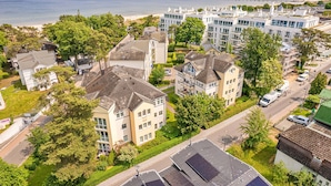 Un quartier résidentiel en bord de mer, avec des bâtiments modernes et traditionnels, une plage et un pont en arrière-plan.