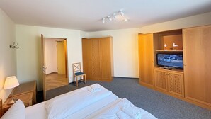 Une chambre d’hôtel avec un lit, une télévision, des armoires en bois, une chaise et une lampe.