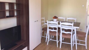 Un espacio habitable compacto con comedor, televisor y armario.