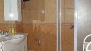 Un baño con lavamanos, mueble y cabina de ducha, todo en color blanco.