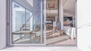 Un interior moderno con una puerta de cristal que da a una escalera y una zona de cocina.