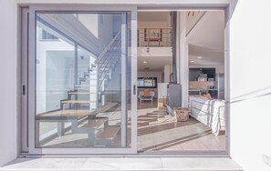 A modern interior with a glass door leading to a staircase and a kitchen area. - 4 bedroom awesome home in Cómpeta (Cómpeta)