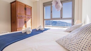 Habitación de hotel con una cama grande, un armario de madera y vistas a montañas desde la ventana.