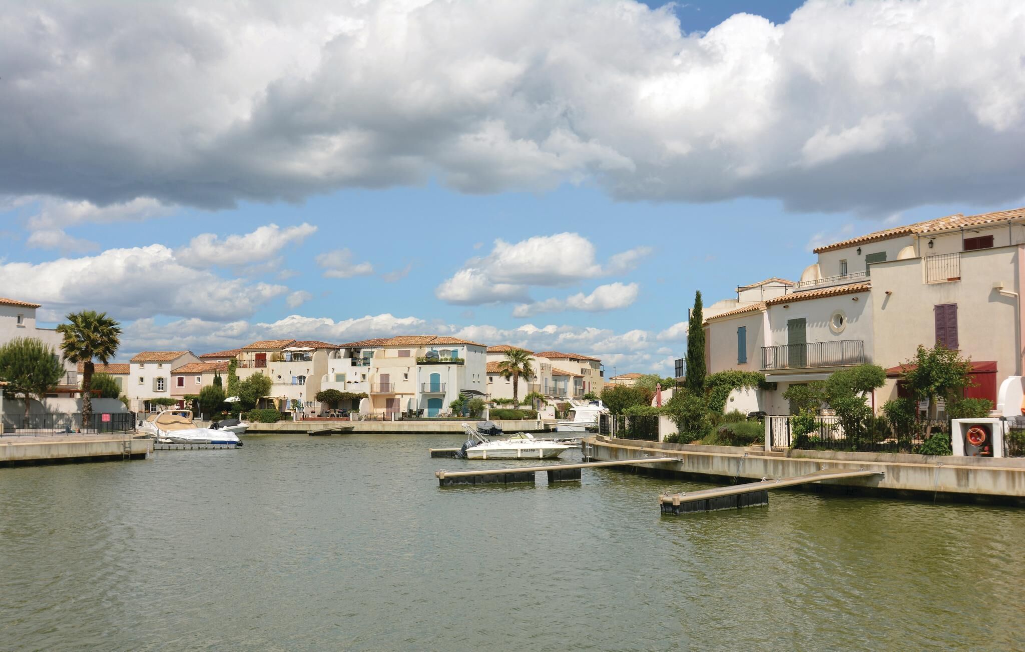 A marina with boats docked, surrounded by buildings with Mediterranean architecture.