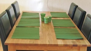Una mesa de comedor con individuales verdes, sillas negras y un cuadro en la pared.