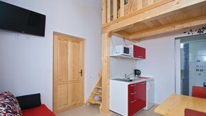 A compact kitchen with a microwave, sink, and red cabinets. A wooden staircase leads to a loft area. - Awesome apartment in Pula with WiFi (Pula)