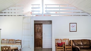 Habitación estilo loft con puerta de madera, una mesa de comedor con sillas, un sofá de cuero marrón y un cuadro en la pared.