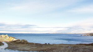 Un paisaje costero con costa rocosa y mar tranquilo.