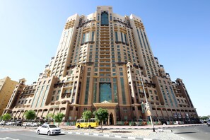 A tall, multi-story hotel with a central entrance and balconies. - Piks Key - Spring Tower (Dubai)