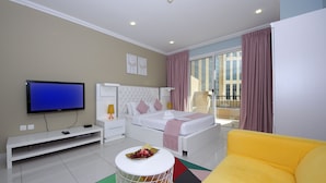 Une chambre d’hôtel moderne équipée d’un lit, d’une télévision, d’un canapé et d’une petite table agrémentée de fleurs.