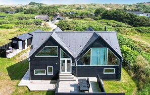 A modern two-story house with a steep roof, large windows, and a deck. - Beach front home in Blokhus with WiFi (Blokhus)
