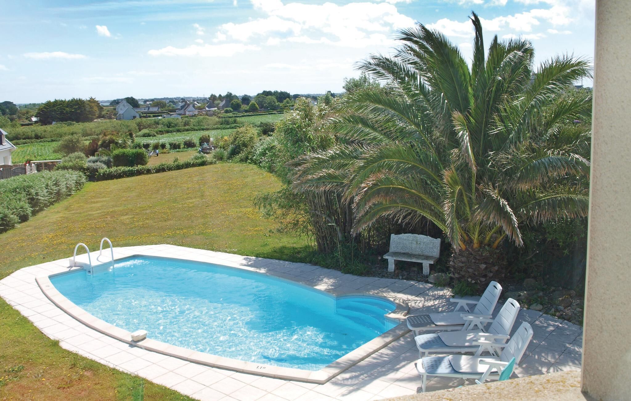 Une piscine offrant une vue sur un paysage rural, avec des maisons et de la végétation.