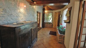 Ein rustikales Interieur mit Steinwand, Holzbalkendecke und Fliesenboden.