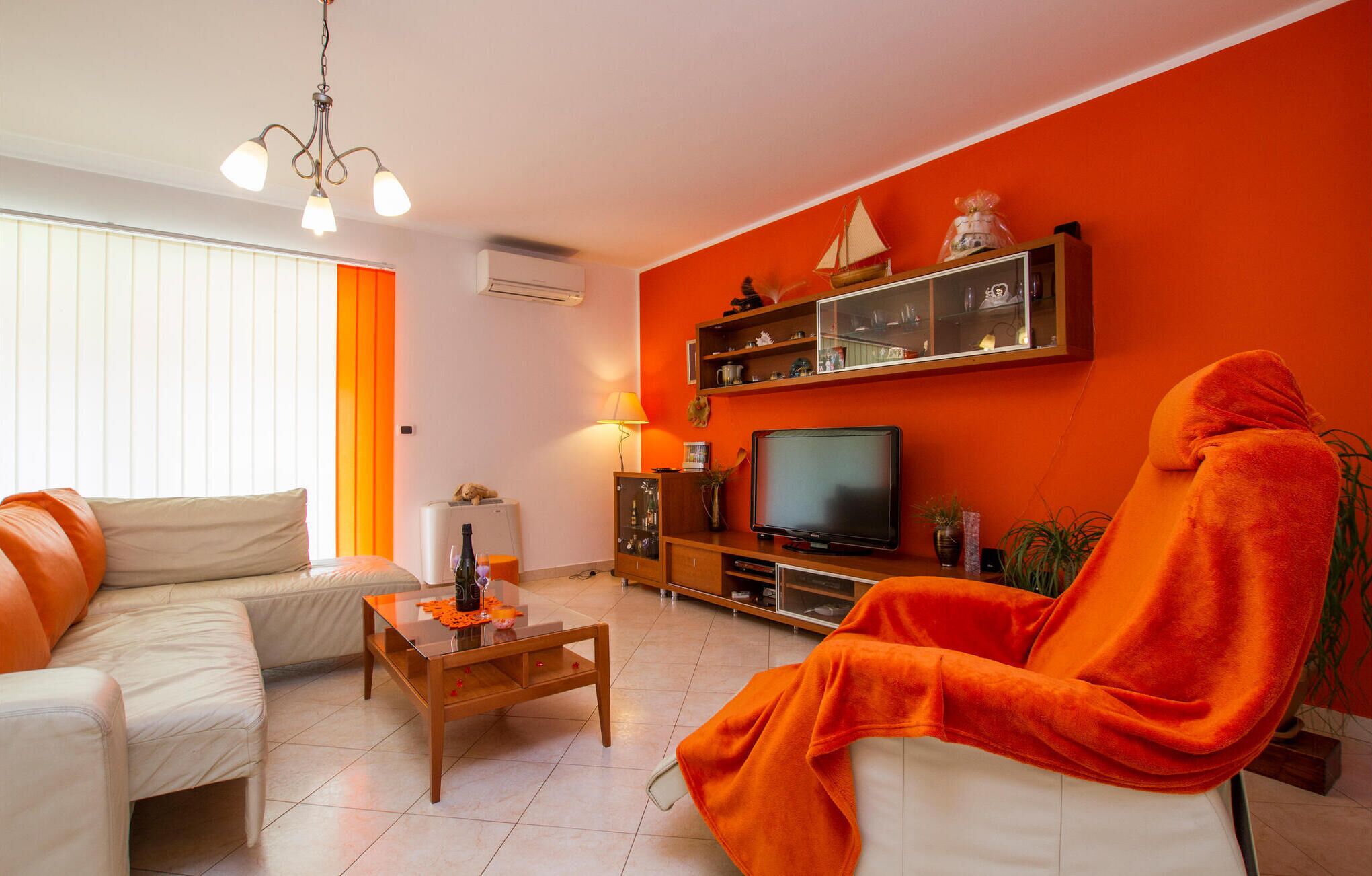 Ein Wohnzimmer mit einer Couch, einem Couchtisch, einem Fernseher und einer roten Wand.