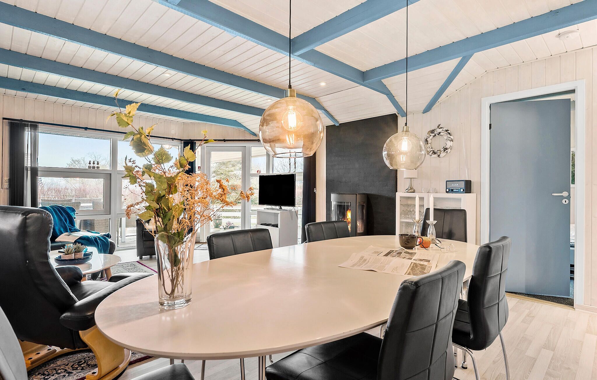 Un espace repas moderne avec une table ronde, des chaises noires et un vase rempli de fleurs.