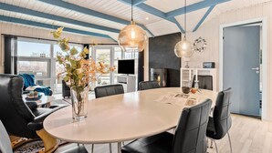 Un espace repas moderne avec une table ronde, des chaises noires et un vase rempli de fleurs.