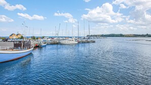 Un port de plaisance avec des bateaux amarrés, une jetée s’avançant dans l’eau et un ciel dégagé.