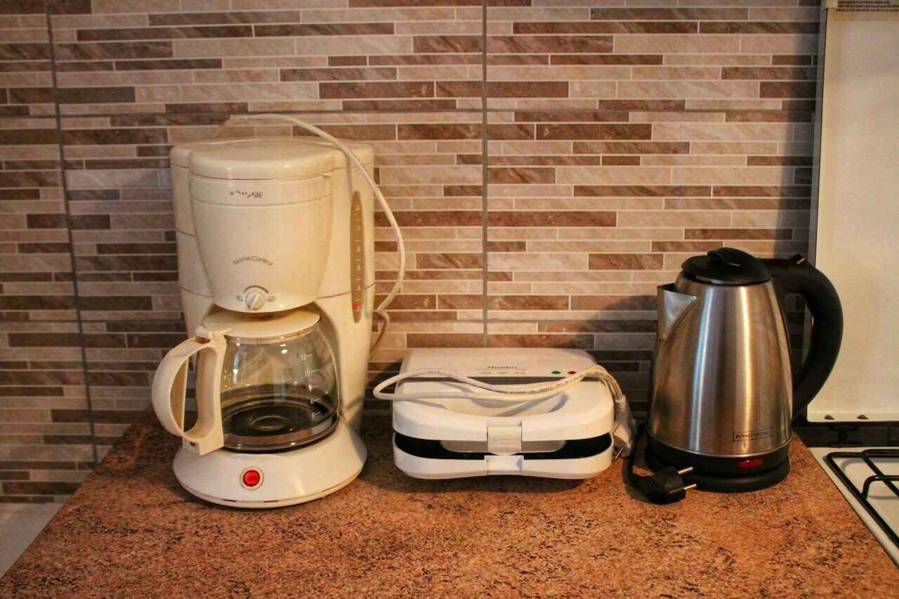 A kitchen with a coffee maker, a kettle, and a portable charger on the counter.