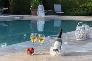 A poolside setting with a champagne bottle, glasses, strawberries, and a decorative lantern.