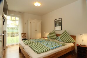 Una camera da letto con un letto, un comodino, una lampada, un armadio e una finestra con persiane.