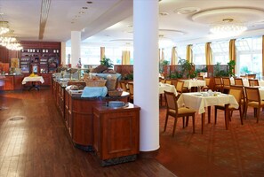 Un ristorante con banconi bar in legno, tavoli, sedie e ampie finestre con tende.