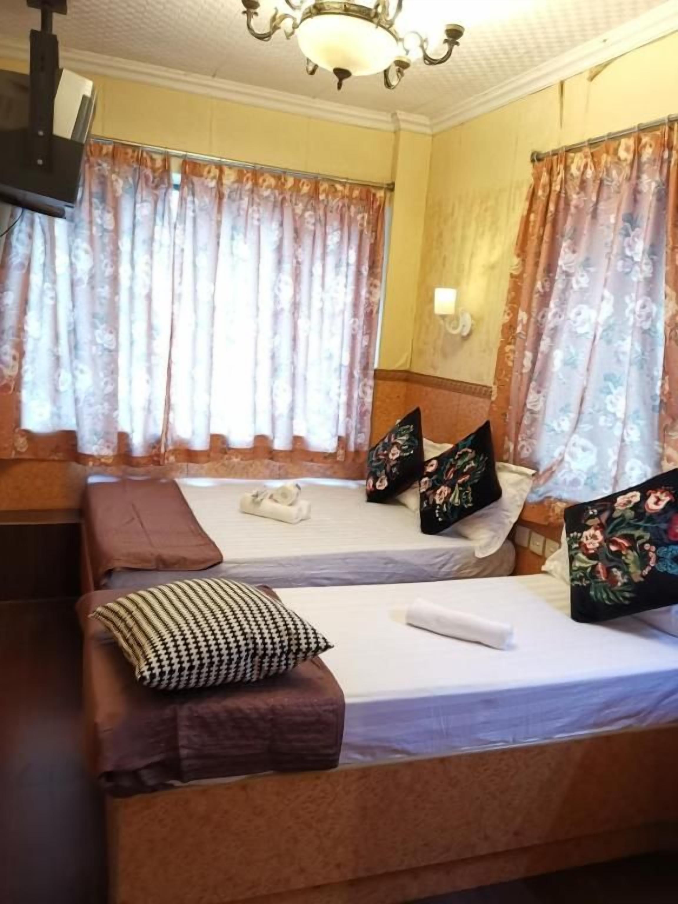 A hotel room with two beds, a sofa, and a television.