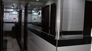 A corridor with a reflective glass partition, a tiled floor, and ceiling-mounted lights.
