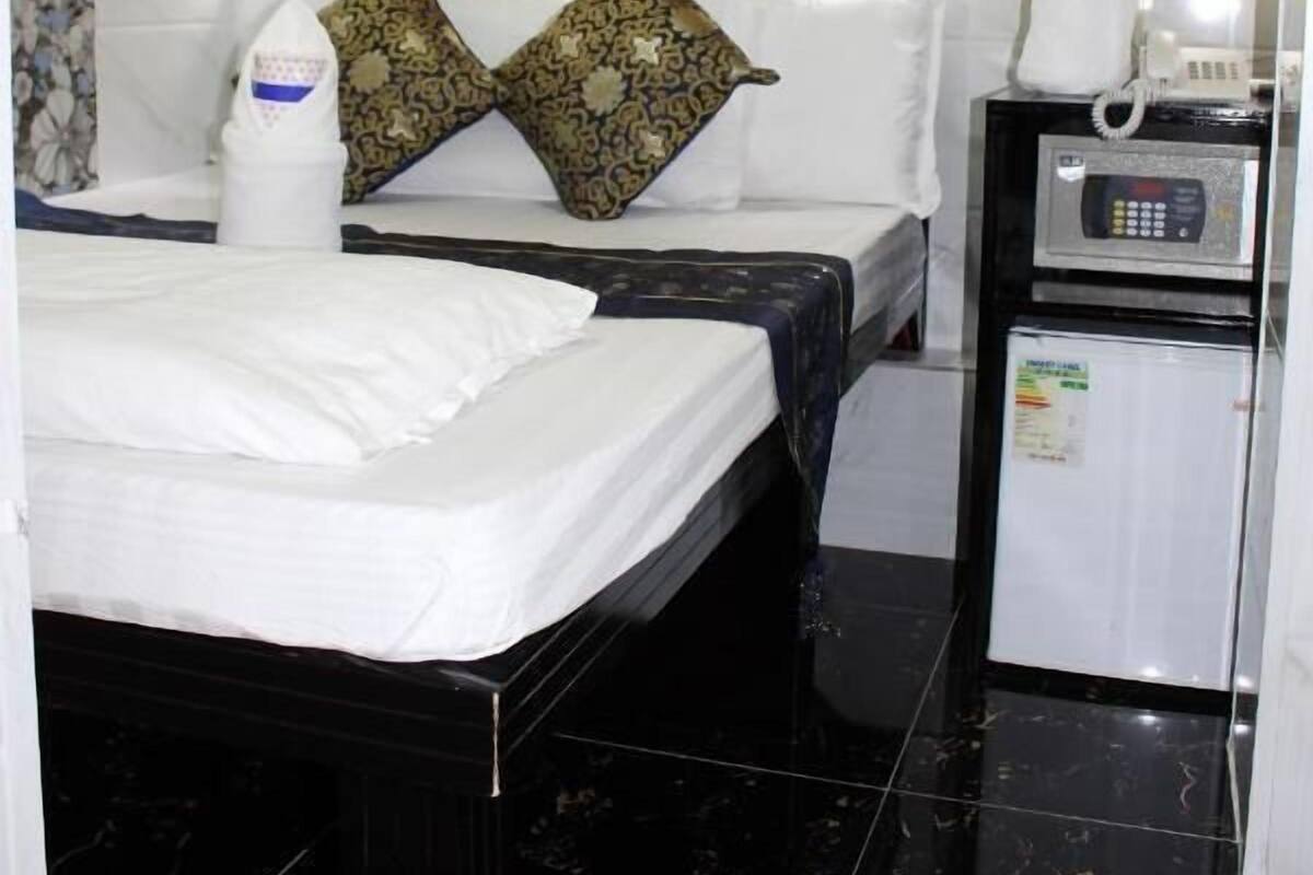 A hotel room with two beds, a minibar, and a flower arrangement.