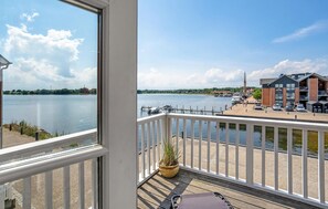 Een balkon met uitzicht op een jachthaven, boten en gebouwen aan de overkant van het water.