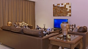 Ein modernes Wohnzimmer mit einem braunen Ledersofa, einem Glastisch und einem Flachbildfernseher.