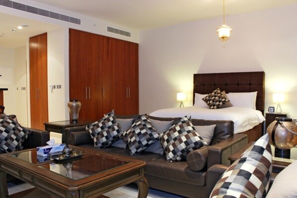 A hotel room with a large bed, a sofa, a coffee table, and a wardrobe.